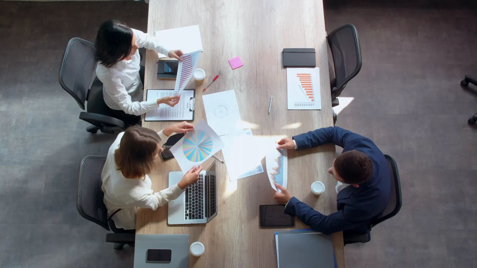 Two advisors reviewing reports with clients at a table, seen from above