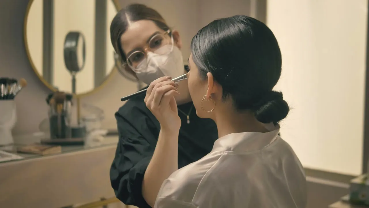 A makeup artist working at a round mirror
