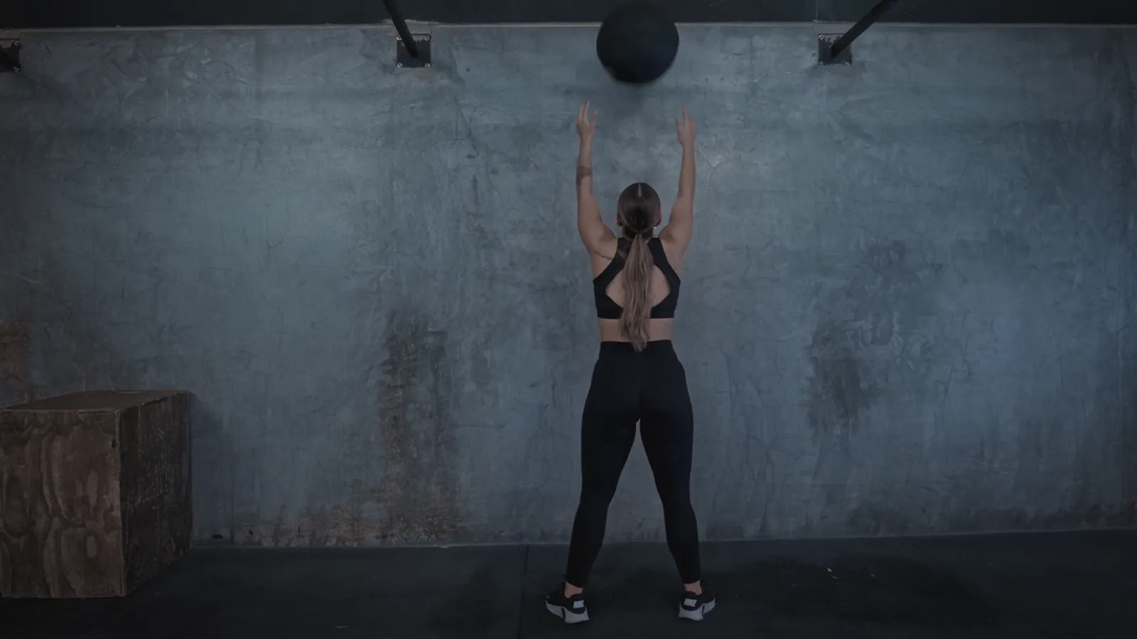 A woman throwing a medicine ball at a wall