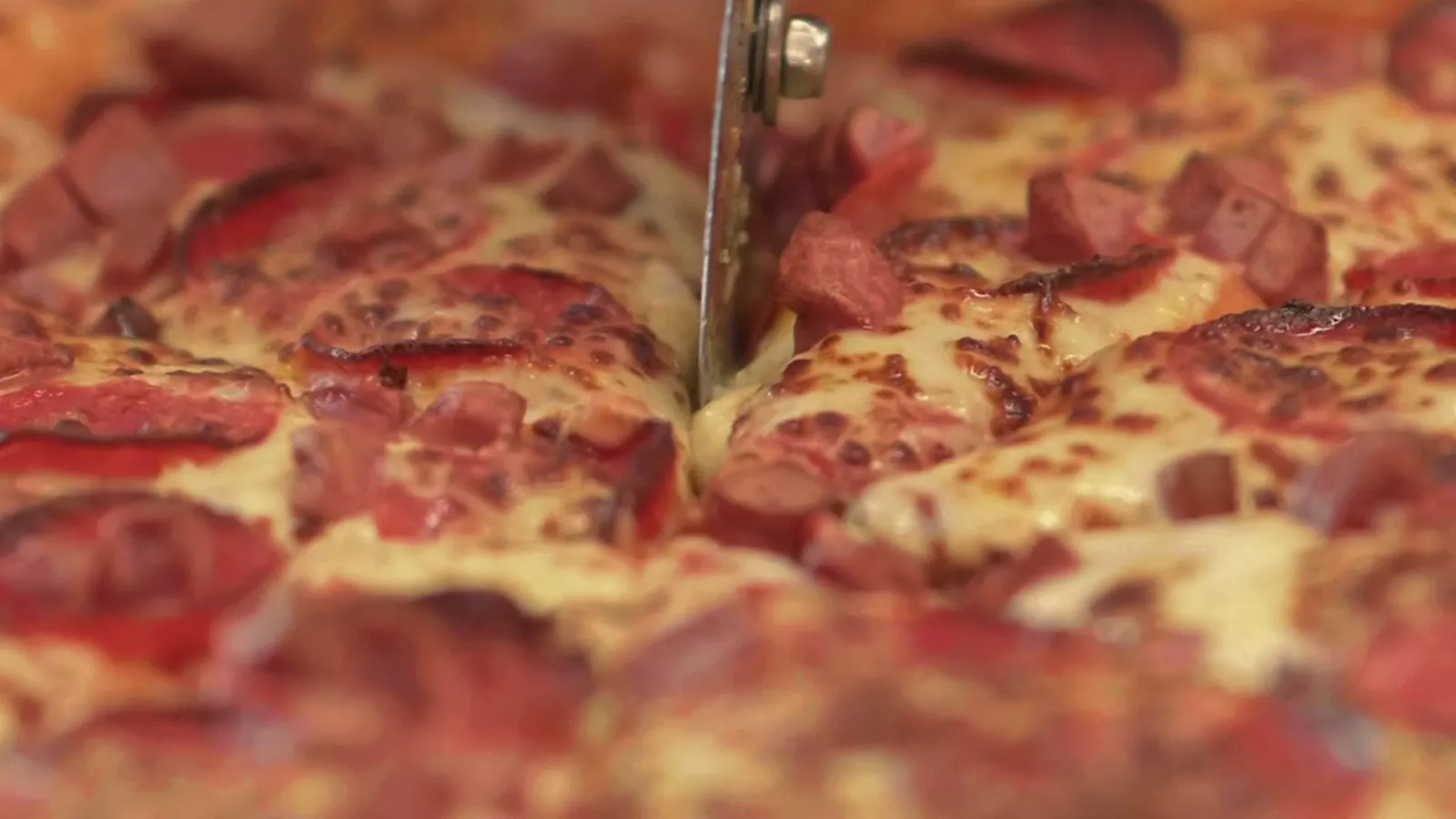 Pizza being cut into slices