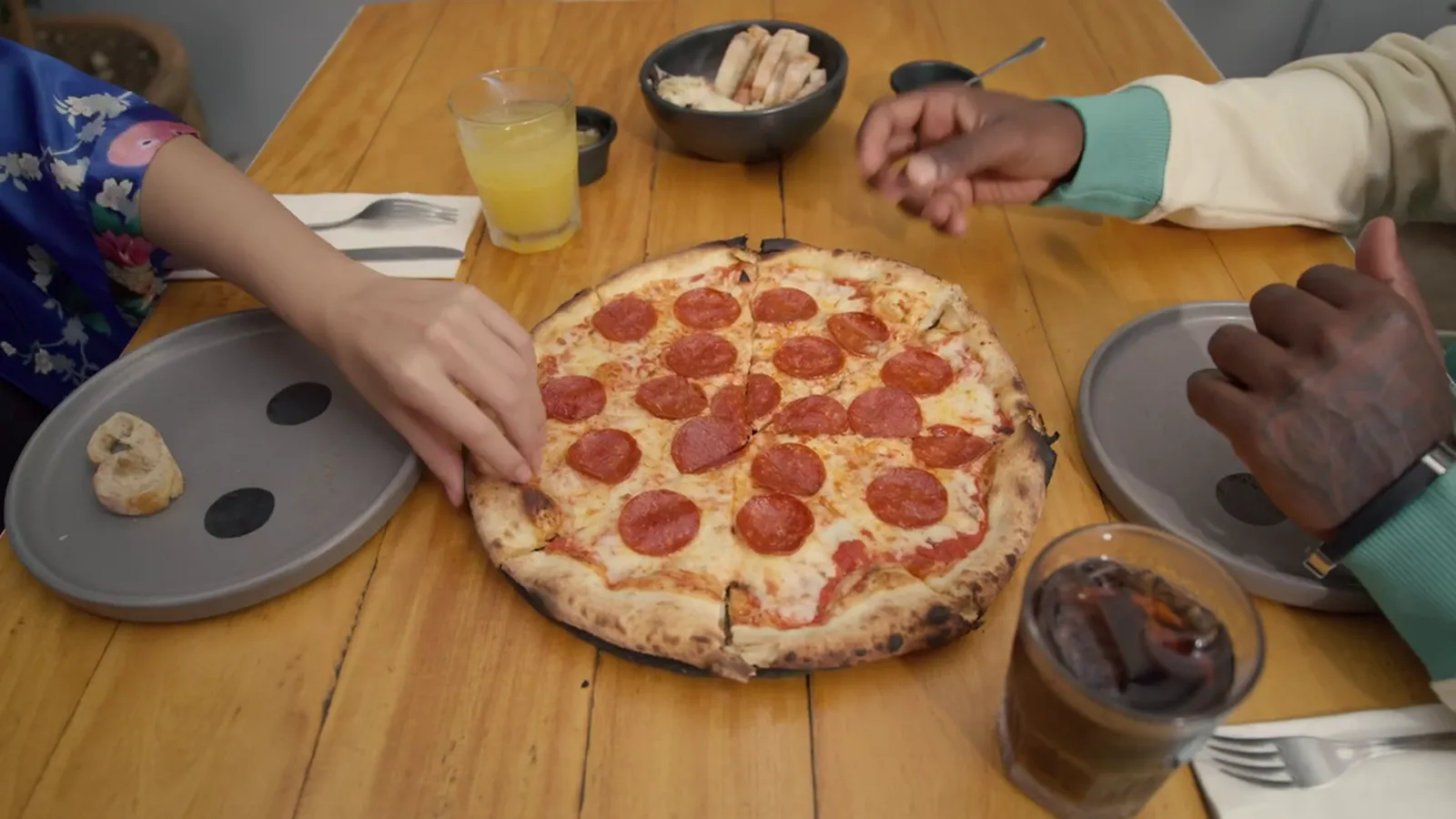 Friends sharing a pepperoni pizza at a long wooden table